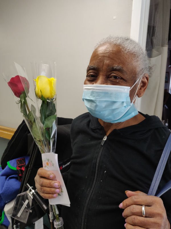 Person wearing mask holding flowers