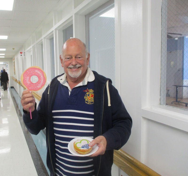 Man holding donut on plate and donut sign